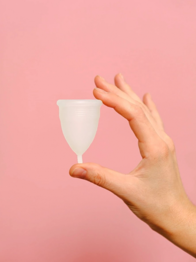 Photograph of a hand holding up a menstrual cup.
